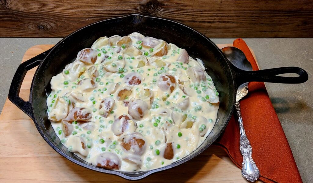 Creamed peas and new potatoes in a cast iron pan make a great side dish for easy Yule dinner ideas and recipes for a magical feast. 