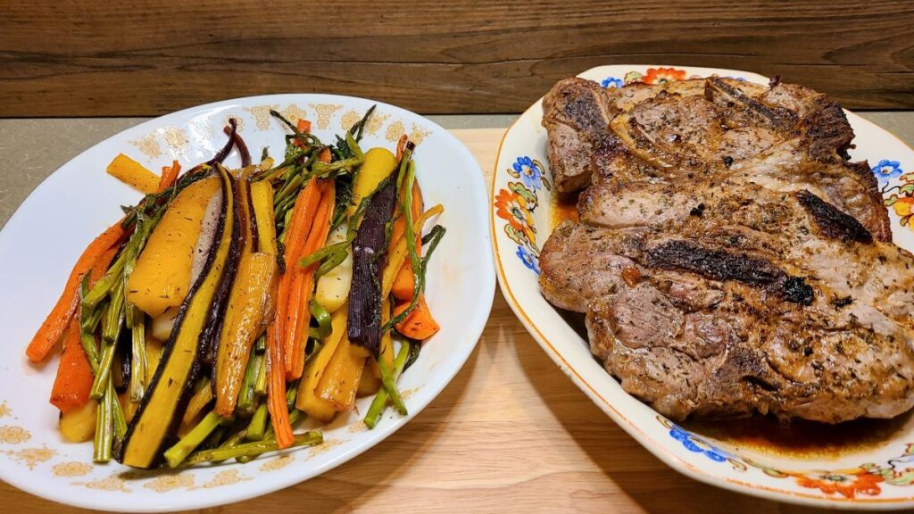 2 platters side by side. One with simple low carb baked and broiled juicy pork chops and the other with roasted carrots and asparagus. 