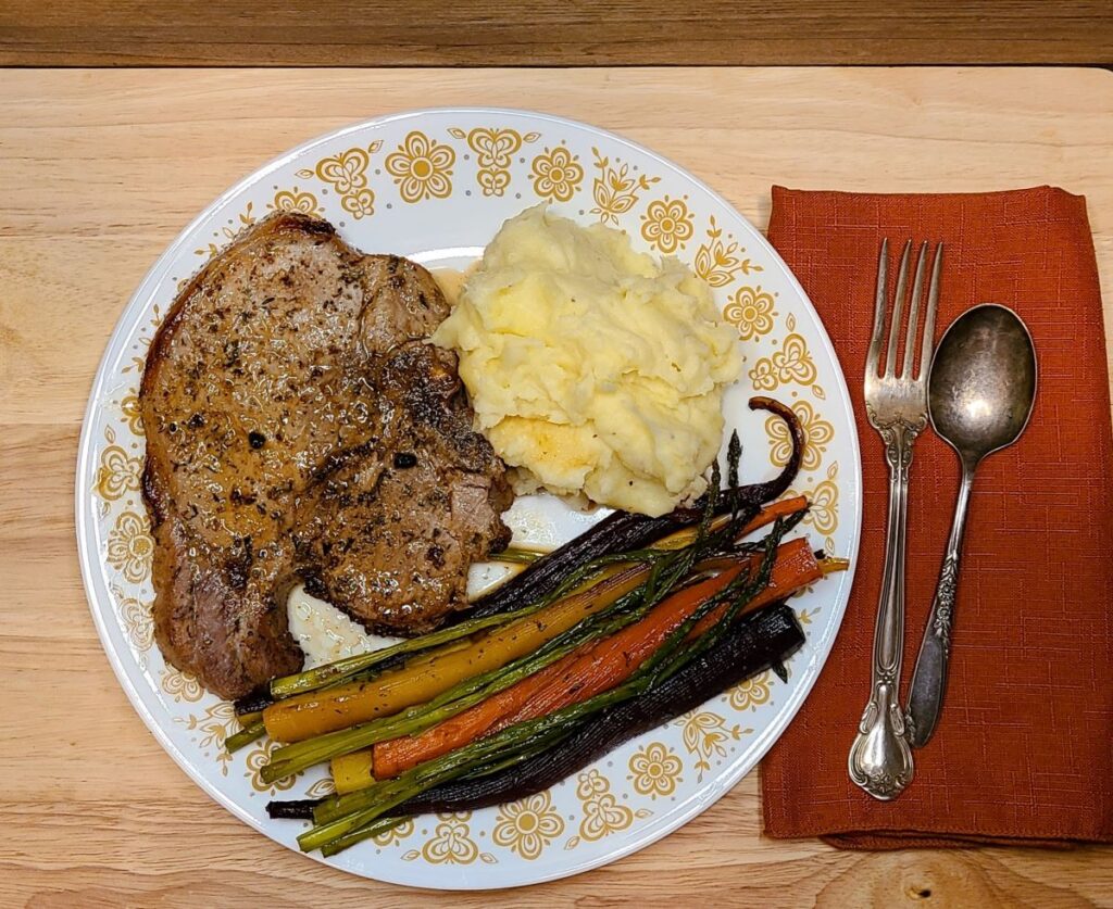 Dinner plate with a pork chop, mashed potatoes, and roasted veggies. 