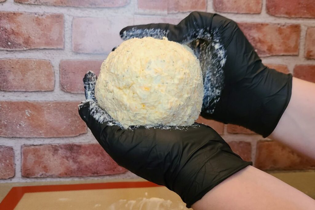 Gloved hands rolling a cheese ball