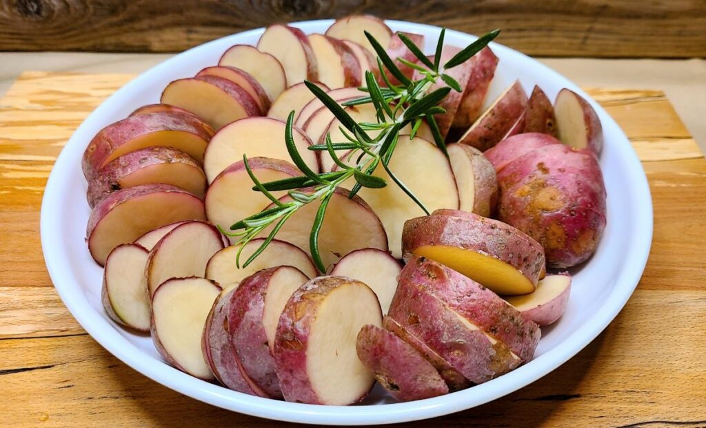 Cut potatoes in a white bowl to make  Easy Oven Roasted Potatoes With Rosemary Butter.
