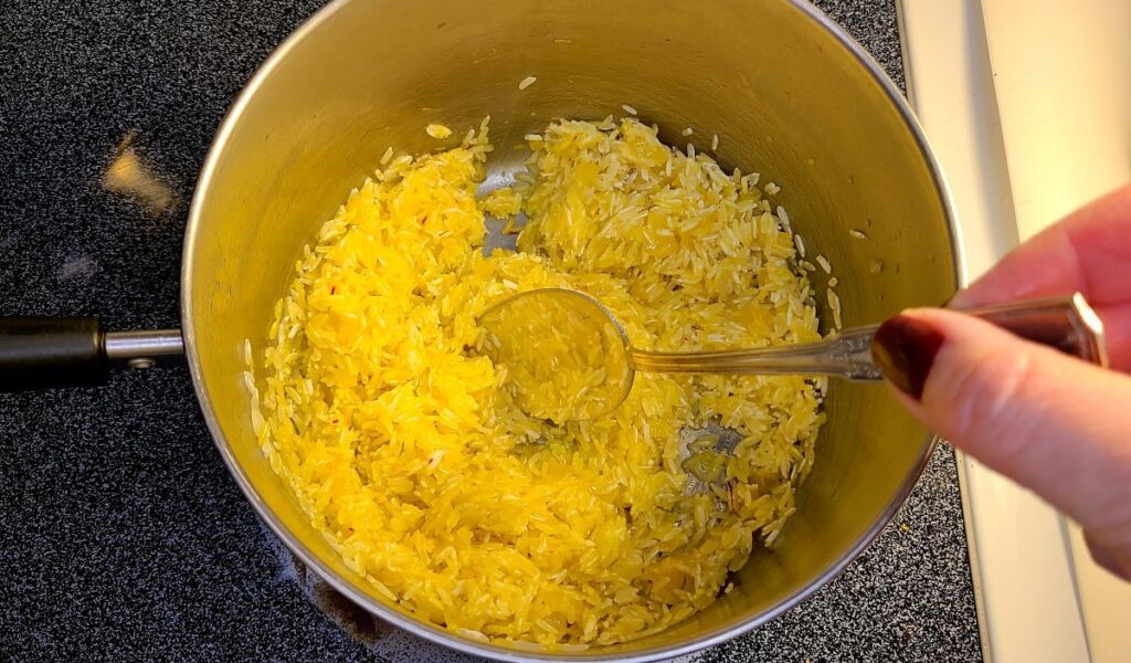 Stirring rice and saffron spices to make easy saffron rice recipe and the health benefits.