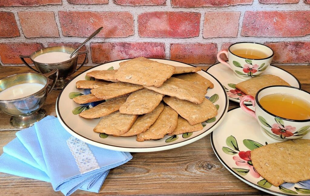 Plate of old fashioned simple brown sugar Clifford tea cookie recipe with tea cups and a silver cream and sugar dish.