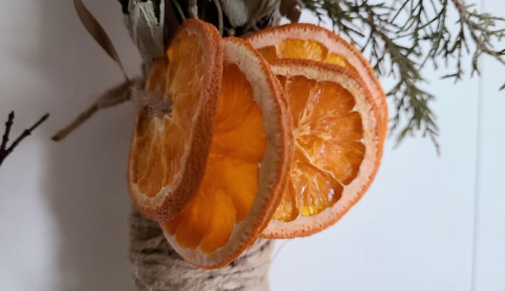 Sliced and dried oranges tied to a broom handle. 