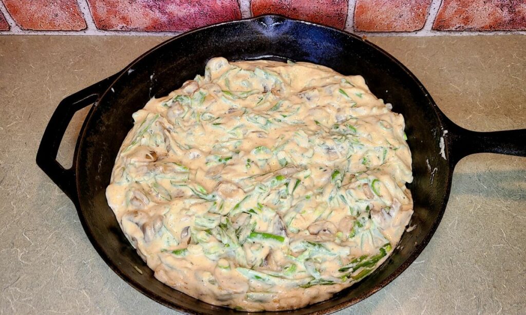 The ultimate make-ahead homemade green bean casserole in a cast iron skillet by a brick wall.