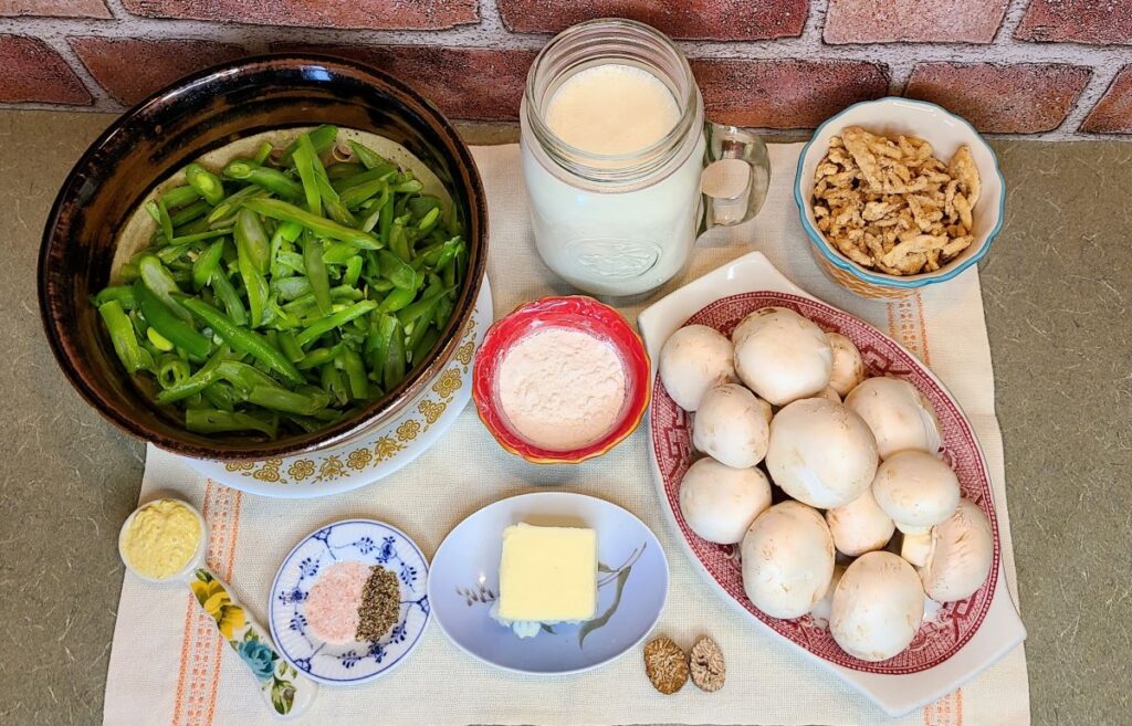Ingredients to make The ultimate make-ahead homemade green bean casserole laid out on a pretty place mat. 