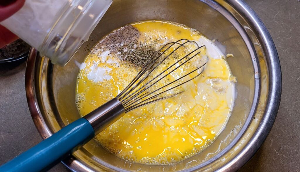 Mixing eggs, cream and seasonings to make Easy overnight sausage, egg, & potato breakfast casserole. 