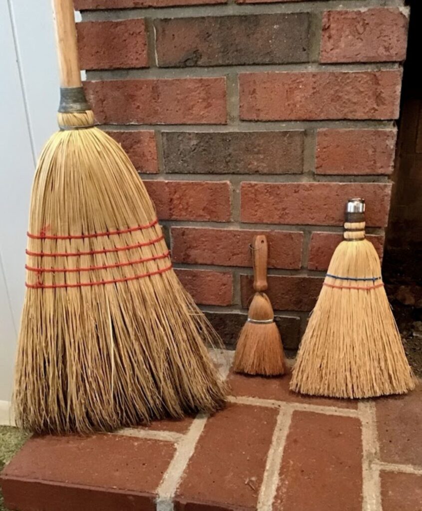 Natural broom/whisk brooms on a brick hearth. 