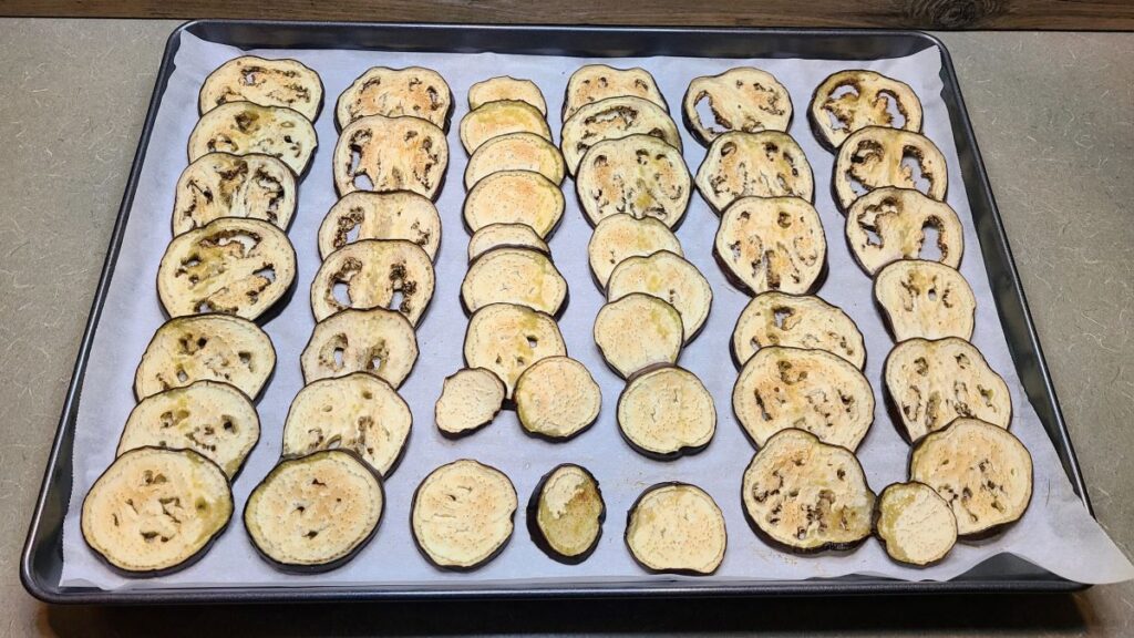 Roasted eggplant slices on a cooking sheet. 