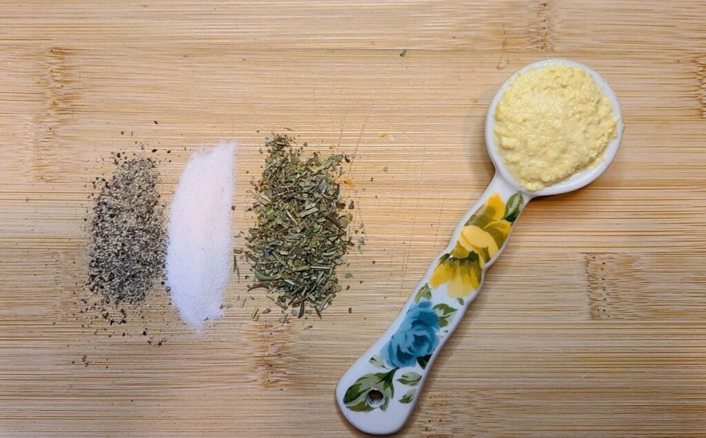 Seasonings and a teaspoon of mustard on a wood board to make Easy overnight sausage, egg, & potato breakfast casserole.