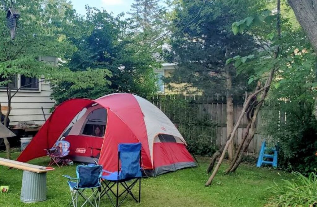 Red tent in a backyard as part of 48 awesome and inexpensive staycation ideas for families.